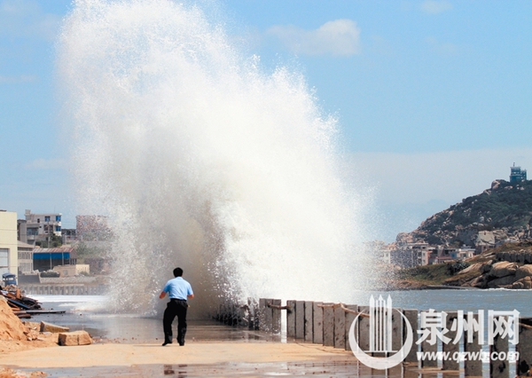 行人躲避冲向岸边的大浪