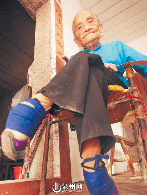 泉州三姐妹300岁 老人安静地坐在椅子上，看着门前的 