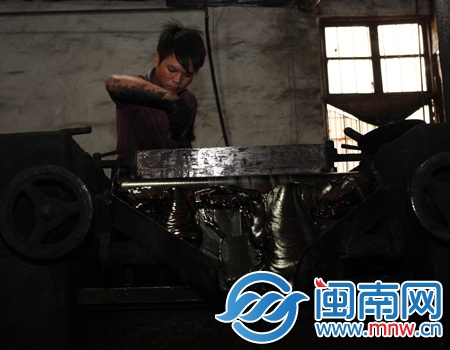 工人王兰福在这台用了10年的老机器边磨墨汁