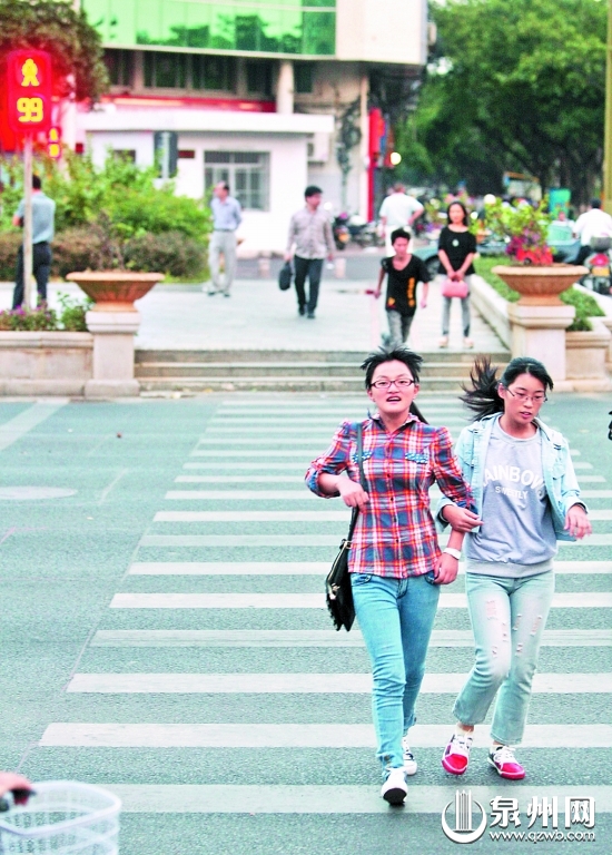 在泉秀街与刺桐路的交叉口，两名女子还没过完马路， 