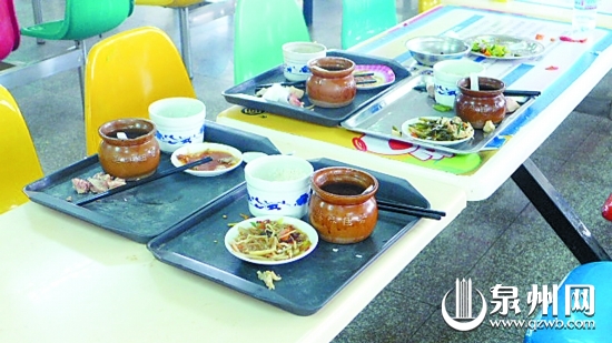 学校食堂餐桌上留着一盘盘剩饭剩菜