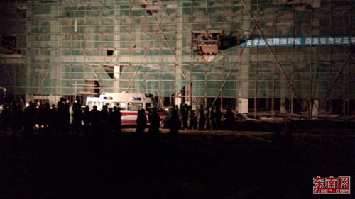 事故所在大楼底下围观的工人，现场停放的救护车和消 