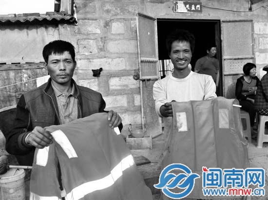 陈镇武（右）与同伴王太平展示落海时穿的救生衣