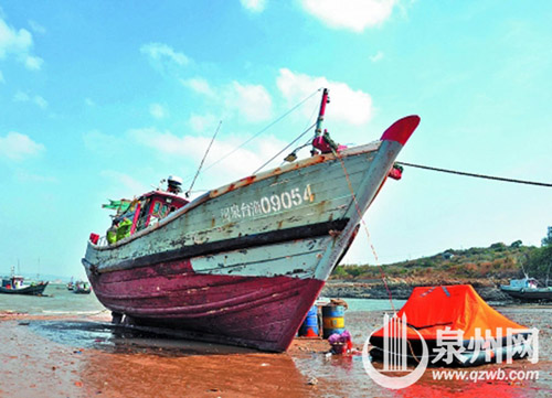 遭受重创的渔船被拖回浮山码头，斜卧在沙滩上