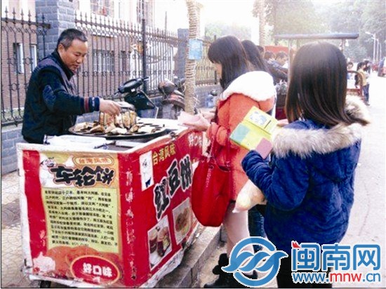 刘卫东(左)在湘潭大学开的这个卖红豆饼的小摊很受师 