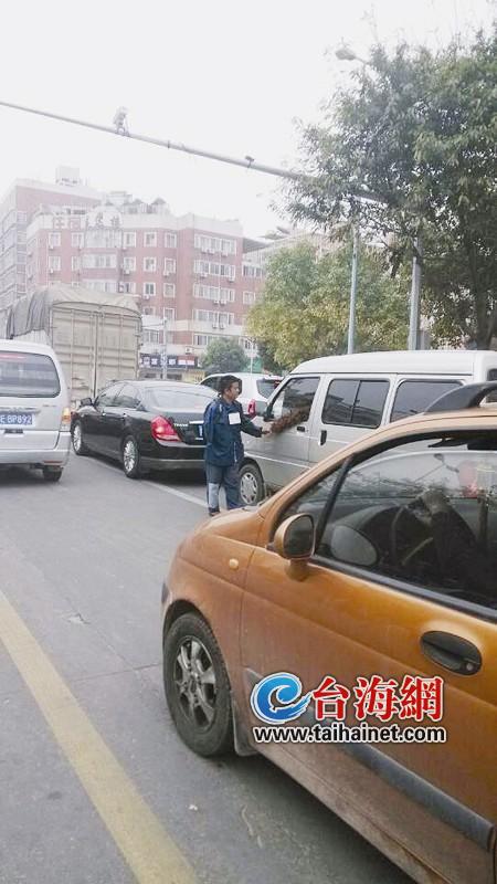 男子拿鸡毛掸子刷别人的车窗，并要钱