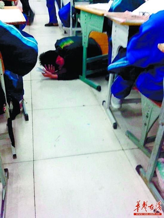 男生双手捂着脑袋，趴在地上