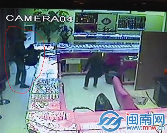 监控中，蒙面男子持枪（画圈处）对着叶女士，叶女士 