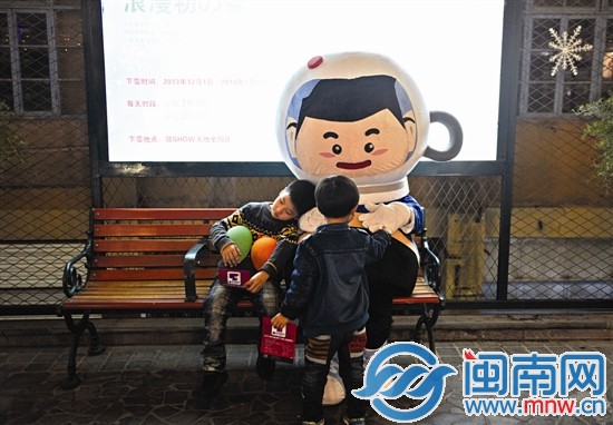 一名小朋友带着淡淡的倦容依偎在大人扮演的“吉祥物 