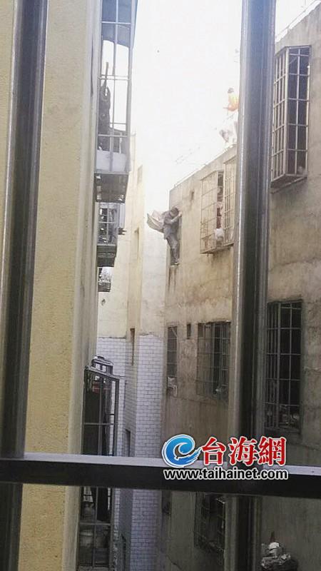 男子攀爬在5楼窗户的护栏上