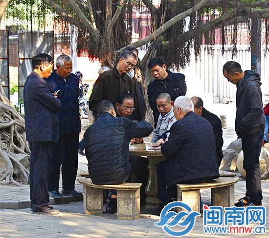 多名老人围着观看打牌