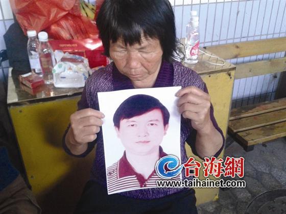 苏明宝的母亲拿着儿子的照片，一脸悲伤