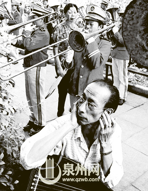 西洋鼓乐队的声音太大，琵琶演奏者不由得捂住了耳朵 