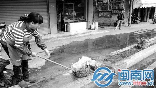 店主刘女士试图用拖把堵破裂的水管