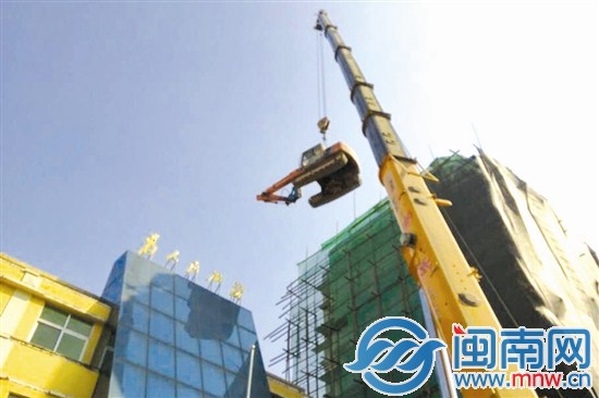 大型吊车将挖掘机吊上楼顶