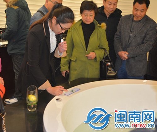 ()辉煌水暖的工作人员演示操作智能化的浴缸