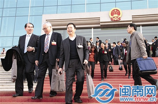 委员们手拿灰色手提袋走出会场