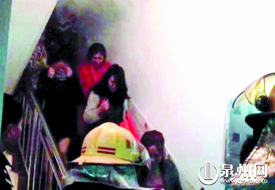 被困女子在消防队员引导下逃生