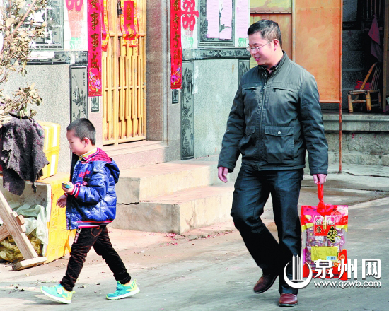 一名父亲提着礼包带着孩子走在去丈母娘家的路上