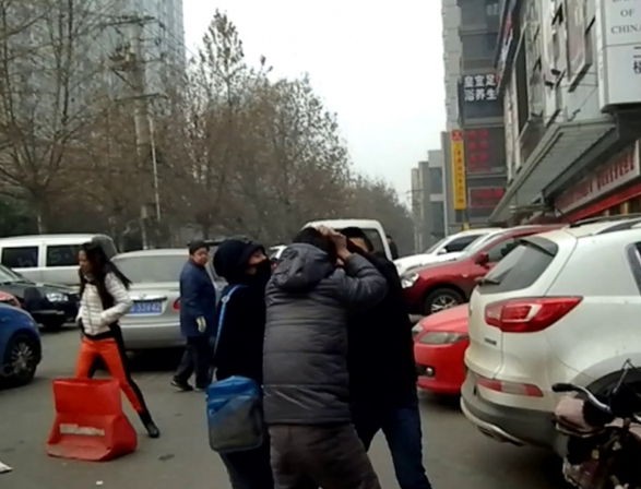 视频截图（右一黑衣男子为城管）