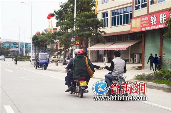 男子骑电动车与摩托车女子手拉手