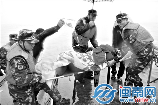 民警有的撑伞，有的抬担架，将还在输液的老人送上警艇