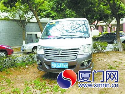 这部公务车辆停在小区绿化带上