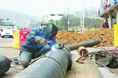 工人正在焊接新的钢管，为燃气管道迁改施工做准备