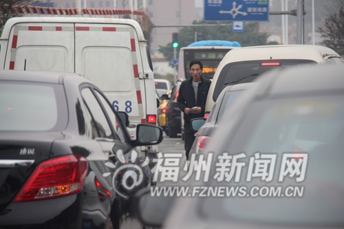 在车流中发小广告的男子
