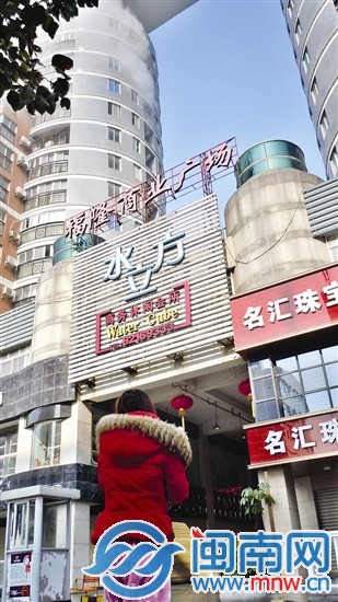 穿着睡衣的居民站在楼下看冒烟的楼层（画圈处）