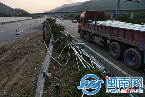 工人将撒落高速路的钢管搬到车上
