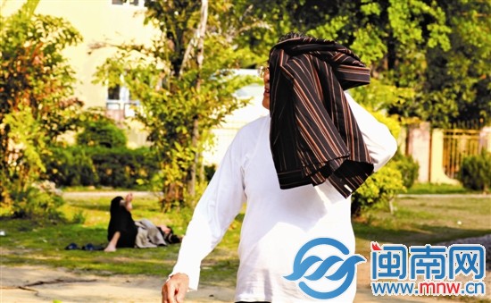 一名老人拿衣服遮太阳
