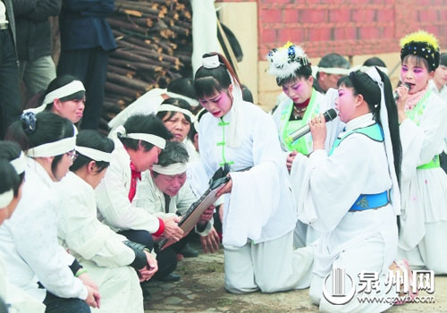 即将出殡，哭灵人在祖祠前一边哭灵一边手捧遗像与亲 