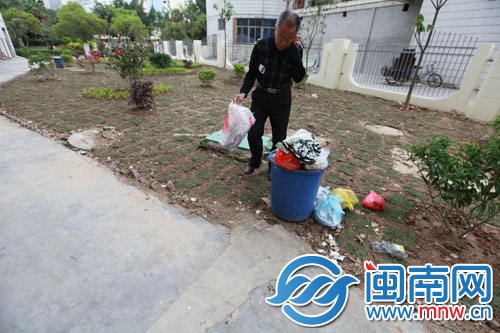 业委会老吕在12号楼下新做的绿化带里捡着被风吹落的 