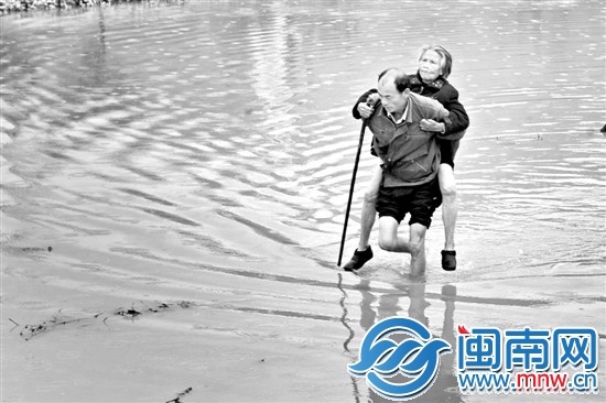 菜农徐先生背着阿婆，从积水处走出