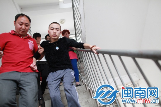 爱心人士汤先生扶着小邓下楼梯