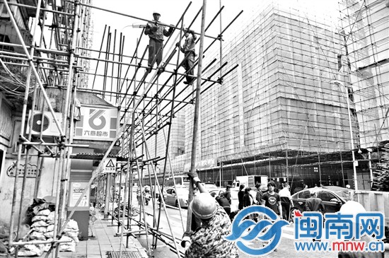 工人在施工时，仍有部分车辆停在过道上