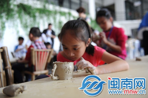 小女孩在陶杯上刻上“张”字
