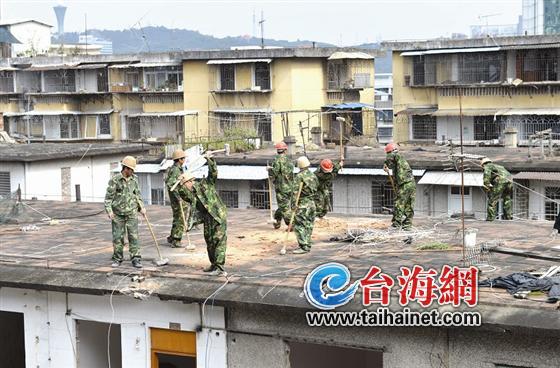 工人挥起大锤敲向屋顶