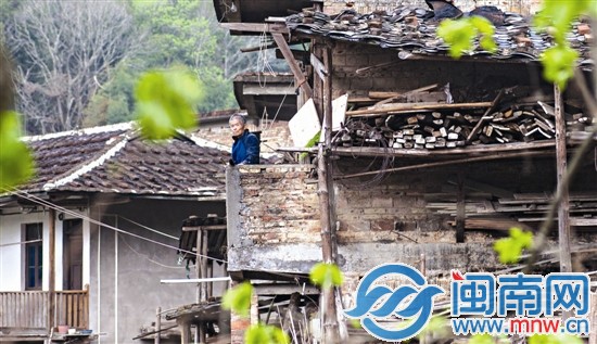 留守的老人站在旧房子的阳台上