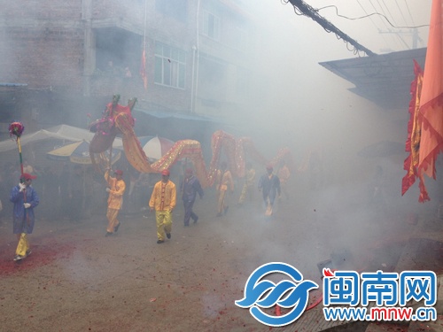 巡游队伍经过门前，村民放起爆竹
