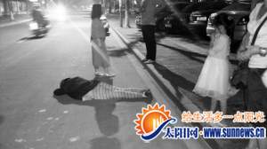 阿婆趴在机动车道上,不少热心人正在守护