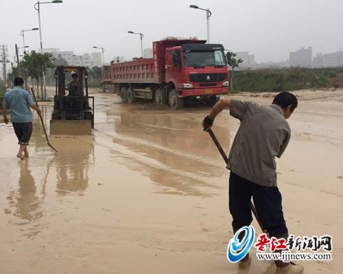 公司员工正在清理门前泥泞路。