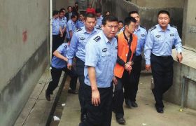 新化县，犯罪嫌疑人伍涛在公安民警的看押下指认现场。