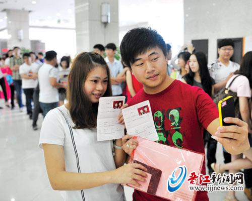 刚领到结婚证的年轻夫妻拿着手机自拍