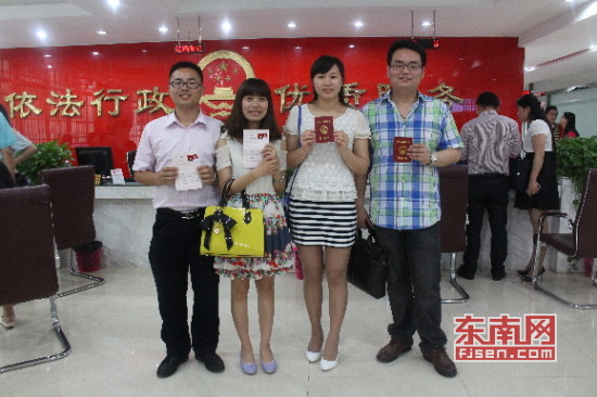 　相约一同来领证的两对新人高兴地举起结婚证让记者 