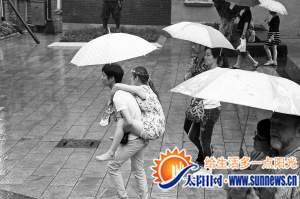 昨日下午,一名男子背着一名女子在雨中行走。