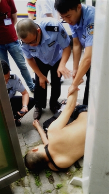 一名男子光着上身躺在路边人行道旁