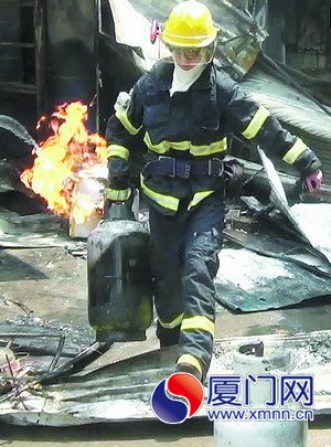 消防员从起火的小吃店内抢出液化气罐。