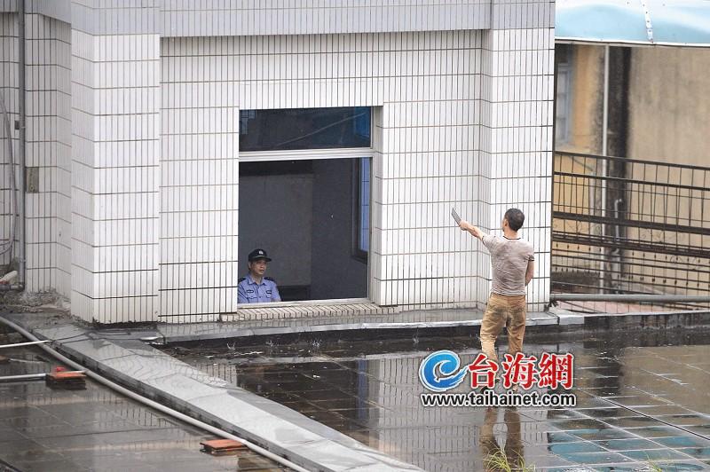 男子持双刀爬上楼顶,警方正在劝说1